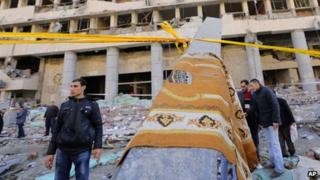 A prayer carpet hangs on a piece of rubble at the site of a blast at the Egyptian police headquarters in downtown Cairo, Egypt, Friday, Jan. 24, 2014.