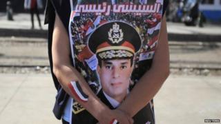 A woman holding a photo of Gen Sisi with the slogan "Sisi is my president"