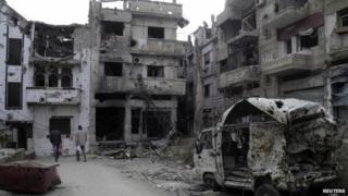 Man walk through damaged buildings in the besieged area of Homs