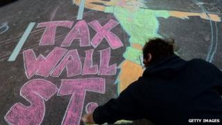 A protester draws "tax Wall Street" on a New York sidewalk using chalk during September 13, 2013, demonstrations