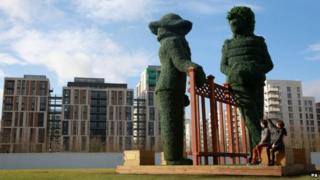 Topiary sculptures depicting neighbours chatting over a garden fence in east London