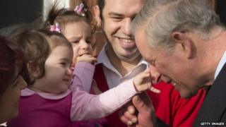 Prince Charles, Prince of Wales jokes with husband and wife Mehmet and Burcin Akbasak with their twin daughters