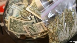 A bag of marijuana being prepared for sale sits next to a money jar in Northglenn, Colorado, on 31 December 2013