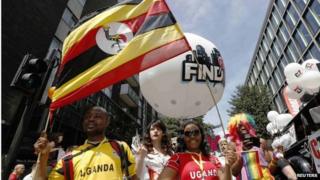Participants waving a Uganda flag and wearing Uganda sports shirts participate in London's annual Pride London parade in June 2013
