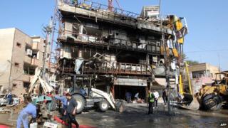 Municipality workers clean the area in the aftermath of an explosion in the Karrada commercial district in Baghdad
