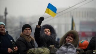 A woman waves a Ukrainian flag as demonstrators gather on a barricade in Kiev on February 9