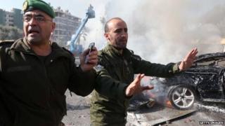 Lebanese security forces stand in front of wreckage of a car blast in Beirut on February 19, 2014.