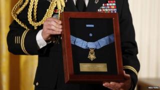 A US Army officer holds a medal case before President Barack Obama presents the Medal of Honor posthumously to the nephew of US Army Chaplain (Captain) Emil Kapaun, for heroism during the Korean War while in the East Room of the White House, 11 April 2013