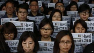 Editorial staff members of the Ming Pao newspaper hold the front page of their newspaper outside the Ming Pao office in Hong Kong, 27 February 2014