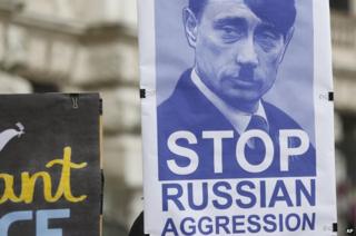 Activists hold a poster featuring Russian President Vladimir Putin as Hitler during a protest in Vienna, 3 Mar 14