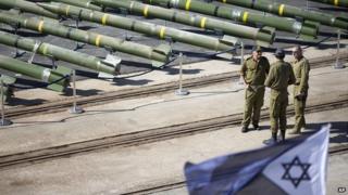 Israeli naval officers stand next to dozens of rockets