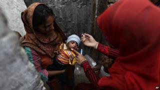 Pakistani health worker Salma Saleem, right, gives a a polio vaccine to a child, in a neighborhood in Islamabad, Pakistan