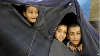 Young Palestinian refugees, who fled the Yarmouk refugee camp in Syria, peer through holes made in their tent as they prepare to move to new houses built by the United Nations Development Programme at the Palestinian refugee camp of Ain El-Helweh, near the southern Lebanese coastal city of Sidon