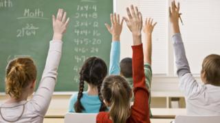 Children raising hands in classroom