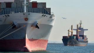 File image of a A T.S. Lines container ship, right, and a Kawasaki Kisen Kaisha Ltd. container ship move through Tokyo Bay in Tokyo, Japan, on Sunday, 18 August 2013