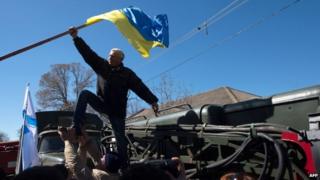 Pro-Russian protesters take down a Ukrainian flag during the storm of Novofedorivka