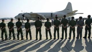 soldiers stand in a line as people board a plane