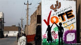 Афганский пешеход проходит мимо стены, украшенной росписью на выборах в Кандагаре
