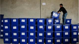 An Afghan election worker stands on a stack of plastic boxes containing election material at a warehouse in Mazar-i-Sharif
