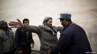 An Afghan policeman searches election workers before the loading of electoral boxes onto trucks for transportation to the polling centres in the northwestern city of Herat on April 3, 2014.