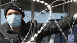 A pro-Russian militant in a surgical mask stands behind barricades near a Ukrainian government building in Donetsk.