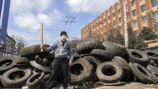 A masked pro-Russian activist poses for a photo in front of barricades at the Ukrainian regional office of the Security Service in Luhansk,