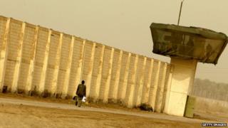 Мужчина проходит мимо тюрьмы Абу-Грейб (2009)