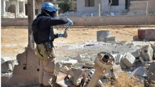 A member of a UN investigation team taking samples near the site of a 2012 chemical attack