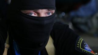 A masked pro-Russian activist guard looks through a window of the regional administration building seized in Donetsk (18 April 2014)