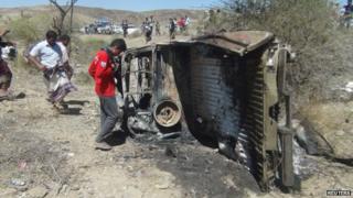 People inspect the wreckage of a car hit by an air strike in the central Yemeni province of al-Bayda, 19 April 2014