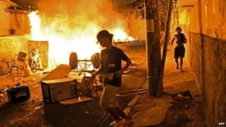 Residents run for cover during violent clashes between protestors and Brazilian Police Special Forces in a favela near Copacabana in Rio de Janeiro, Brazil on 22 April 2014.