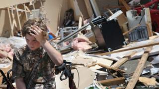 A boy takes sits in front of rubble after a tornado struck Tupelo, Mississippi, on 29 April 2014