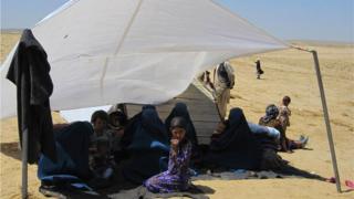 A family shelters under canvas after losing their home in the floods
