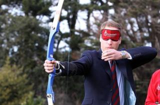 Prince William takes part in an archery lesson, whilst wearing a blindfold to simulate visual impairment, at St Dunstan's centre in 2010