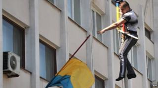 A pro-Russian activist throws down a Ukrainian flag outside the city hall building in Mariupol, 7 May