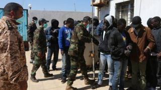 African migrants wait at a Libyan Naval forces post in Tripoli after their boat was intercepted en route to Europe and brought back to Libya, 10 April 2014