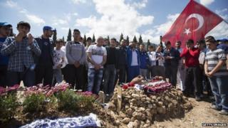 People pray in a Soma cemetery where several miners who died in the Soma mine explosion have been buried, in Soma, Turkey, 18 May 2014