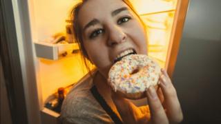 Woman eating from fridge