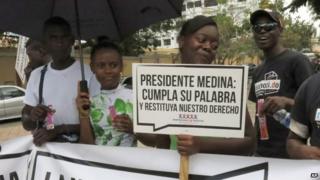 Dominicans of Haitian descent rally in front of Dominican National Palace holding a sign that reads in Spanish "President Medina, stand by your word and reinstate our right" in Santo Domingo on 8 May, 2014