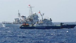 На этом снимке, сделанном 14 мая, показано, что китайское судно береговой охраны (сзади) плывет рядом с вьетнамским судном береговой охраны (спереди) у китайской нефтяной буровой установки в спорных водах в Южно-Китайском море.