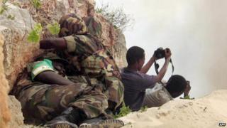 African Union peacekeepers take cover, 15 May 2007, as two Somali photographers point their cameras towards the site where the troops were detonating seized ammunition in Mogadishu, Somalia