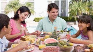 A family eats a meal outside a house.
