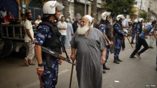 A Palestinian employee paid by Palestinian Authority stands next to a policeman as he waits to receive his salary outside a closed bank in Gaza City June 5