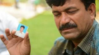 Banoth Shekar, father of missing student B Rambabu Naik and feared drowned in the Beas River in India"s northern Himachal Pradesh state, holds a identification photograph of his son.