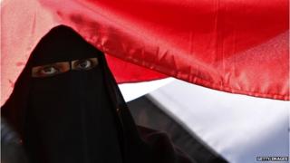 A woman sitting under a flag in Tahrir Square, Egypt