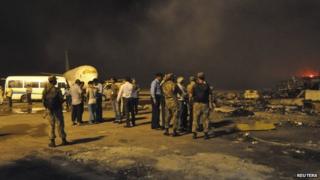 Дым вздыхает, когда сотрудники службы безопасности и сотрудники аэропорта посещают место, поврежденное в результате воскресного талибского нападения на международный аэропорт Джинна в Карачи, 9 июня 2014 года