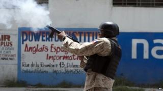 A National Police officer fires tear gas at protestors during an anti-government protest in Port-au-Prince, on 10 June, 2014