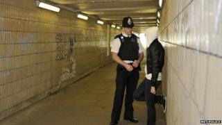 A police officer talks to a young person wearing a hoodie