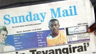 Someone holding up a copy of Zimbabwe's Sunday Mail paper from 2008