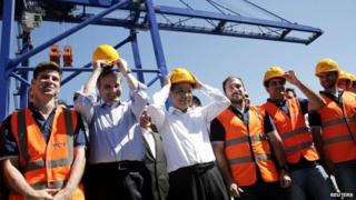 Greek Prime Minister Antonis Samaras (2nd left), and Chinese Premier Li Keqiang (centre) put on helmets as they stand between Greek workers at the port of Piraeus, 20 June 2014